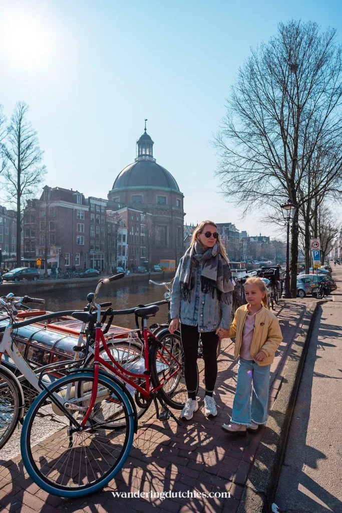 Mother and child walking along a canal in Amsterdam with bicycles in the foreground