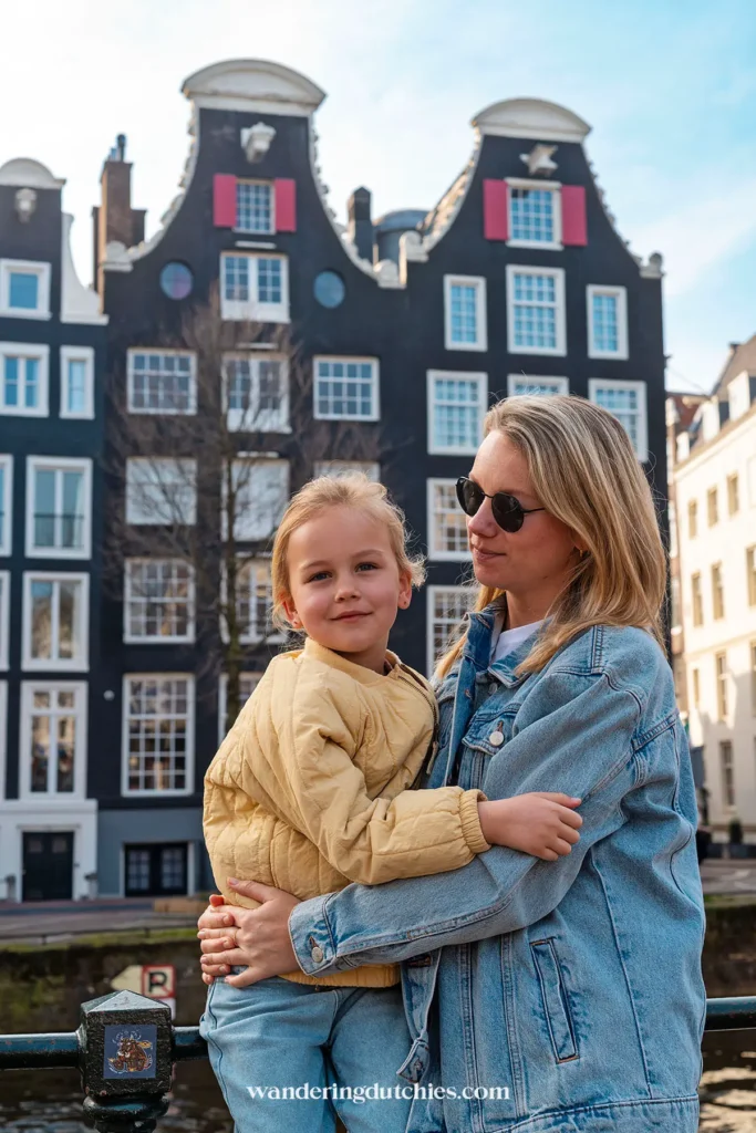 Mother and daughter posing along Amsterdam's canals with historic canal houses in the background.