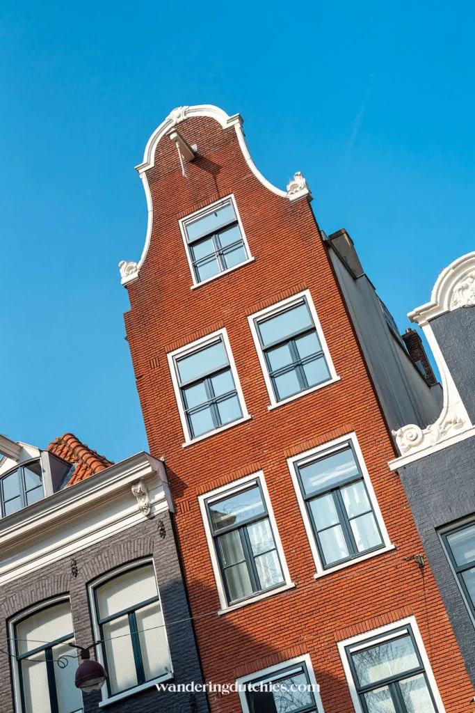 Narrow canal house with red brick facade in Amsterdam