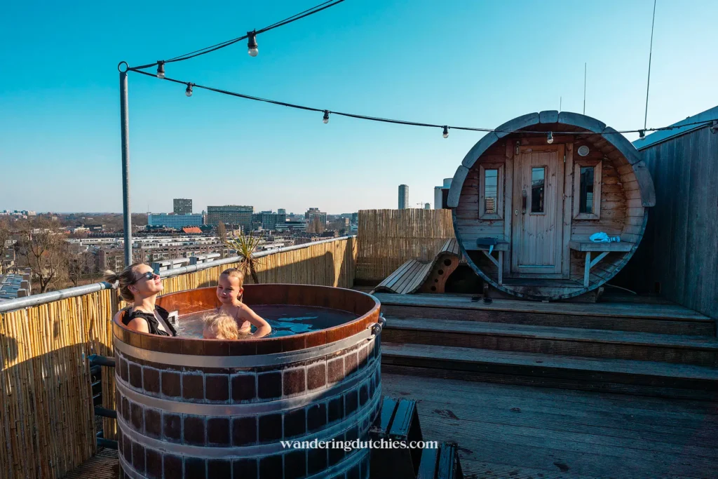 Mother and children enjoying a rooftop hot tub at Volkshotel with views over Amsterdam.
