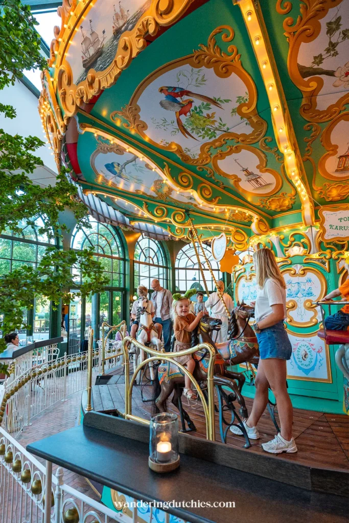 Kind op de draaimolen in Liseberg Grand Curiosa Hotel terwijl moeder toekijkt.